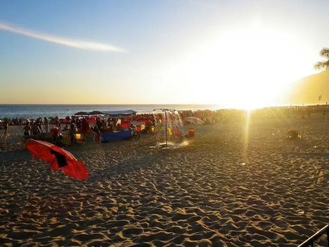 A poetic gathering of individuals at the beach during sunset.