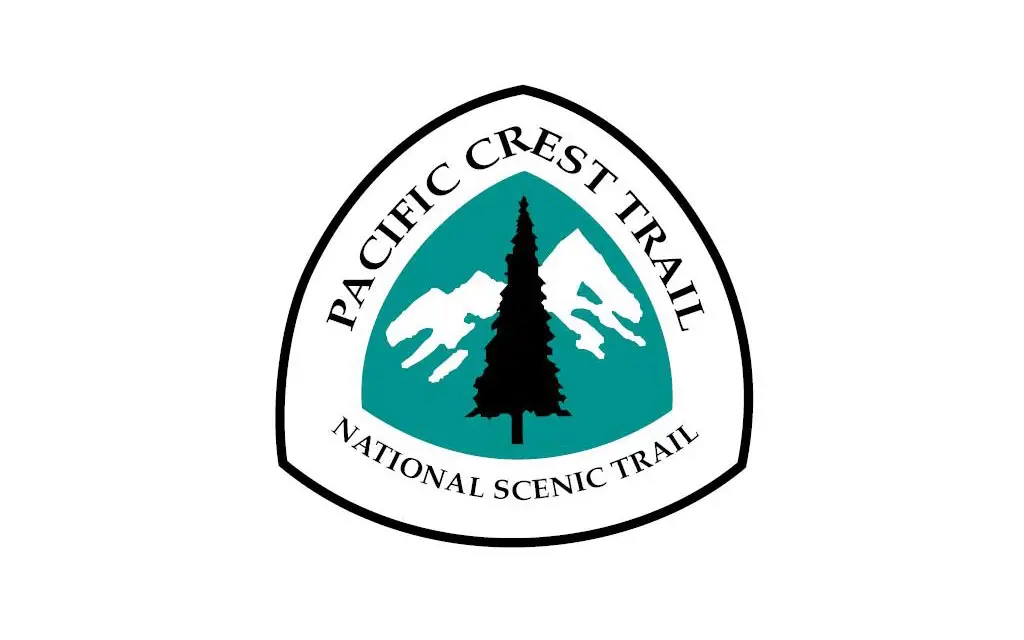 The Pacific Crest Trail logo boasts a triangular emblem featuring a lush green backdrop, a striking white mountain silhouette, and a central black tree. The text proudly displays Pacific Crest Trail atop and National Scenic Trail below.