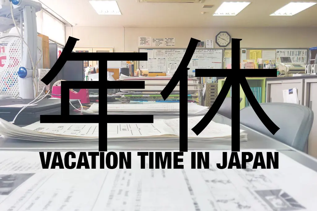 A Japanese classroom features the large characters 年休 (nenkyu) prominently in the foreground. Below, it reads VACATION TIME IN JAPAN. The room is bustling with desks, papers, and office supplies.