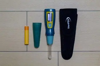 A SteriPEN Ultra water purifier with its protective case rests on a wooden surface. This blue and yellow purifier features a transparent tip and has a blue cap beside it. The sleek black case, emblazoned with SteriPEN in white, complements the device perfectly.