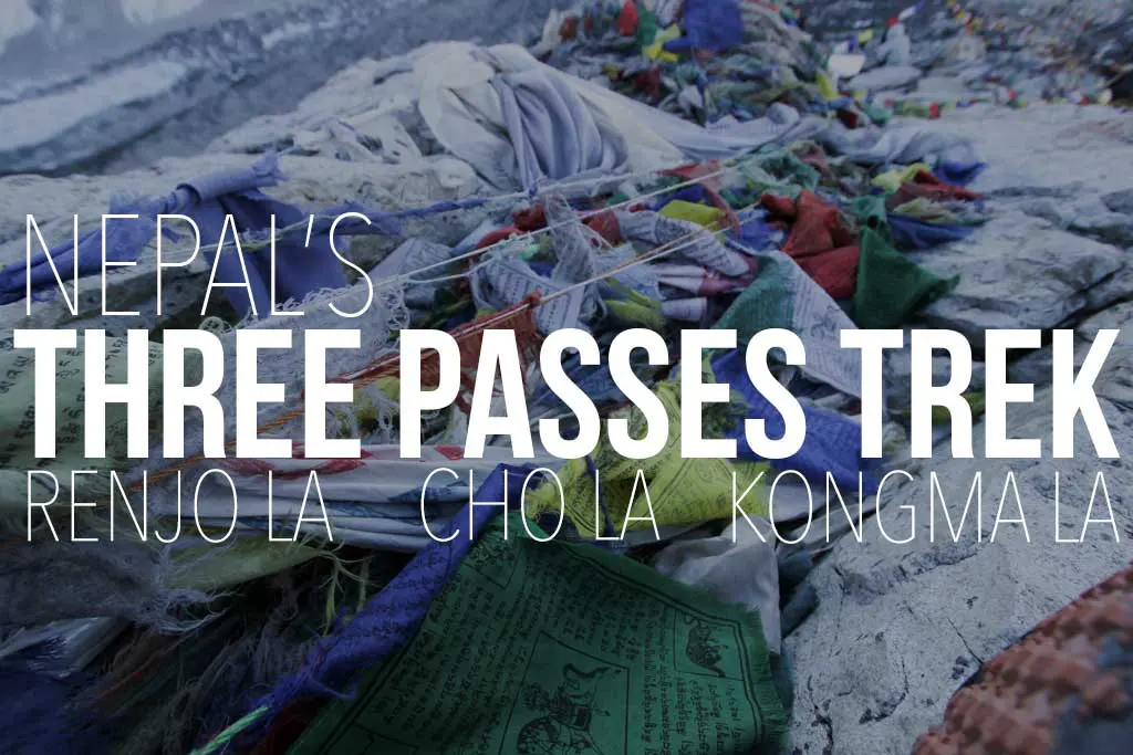 Colorful prayer flags draped across a rocky landscape, with text overlay: Nepals Three Passes Trek - Renjo La, Cho La, Kongma La. Experience the adventure of the Three Passes Trek amidst stunning vistas.