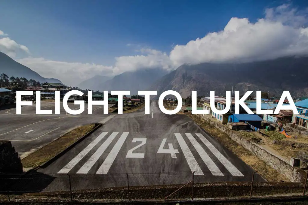 Catching a flight at an airport nestled among mountains, the runway with white 24 markings extends ahead. Blue buildings dot the right, under a partly cloudy sky. Text overlay reads FLIGHT TO LUKLA, perfectly capturing the adventurous spirit of this Lukla flight journey.