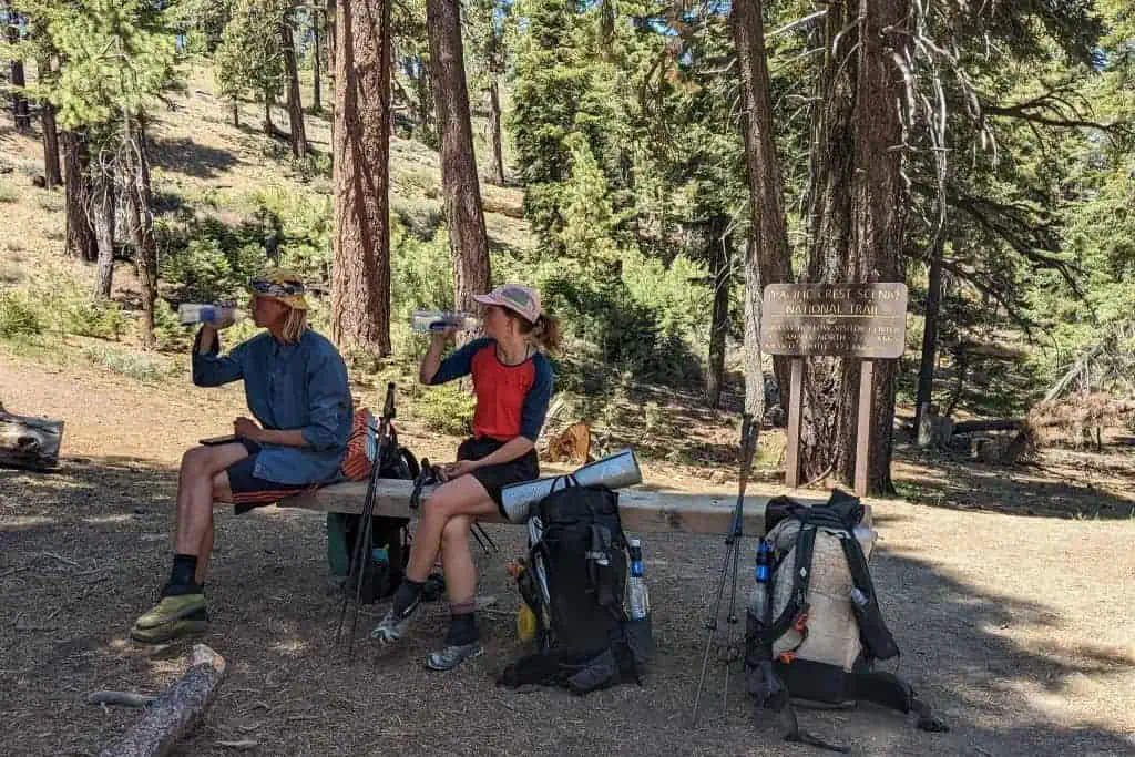 Two PCT hikers sitting and drinking water