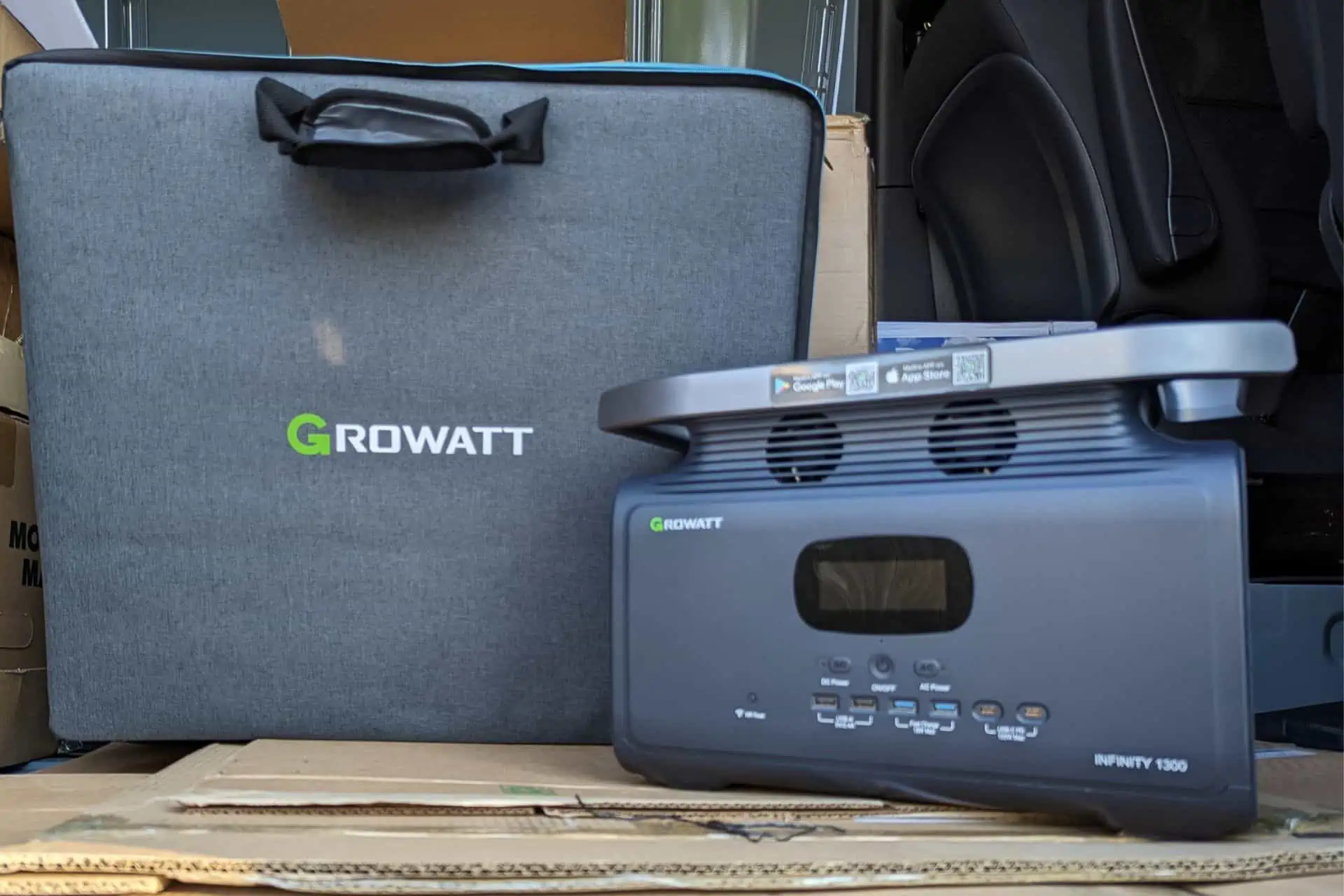 The Growatt INFINITY 1300 Power Station is elegantly perched on a cardboard box, showcasing its digital screen and versatile ports. Beside it, a sleek gray carry bag proudly displays the Growatt logo, completing the portable power package.
