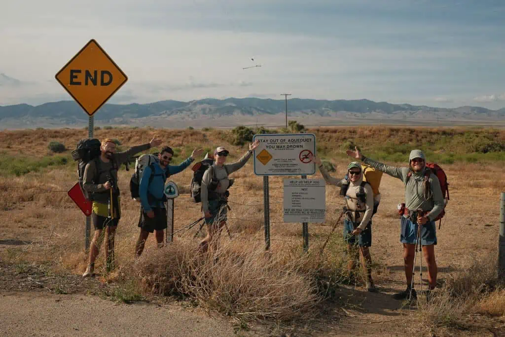 A group of hikers in front of a sign in the desert.