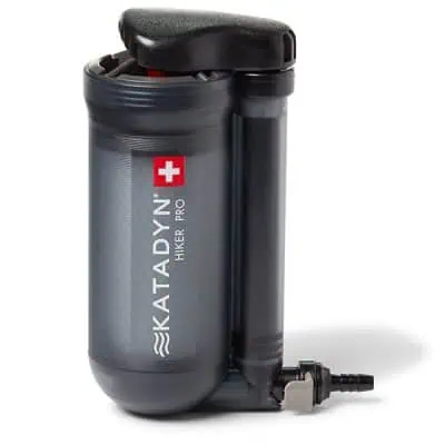 Portable water filter labeled Katadyn Hiker Pro featuring a gray cylindrical body with a black top and connected black tube, included in the JMT Gear Guide 2024. A red internal part is visible through the transparent top area, with a Swiss flag symbol next to the brand name.
