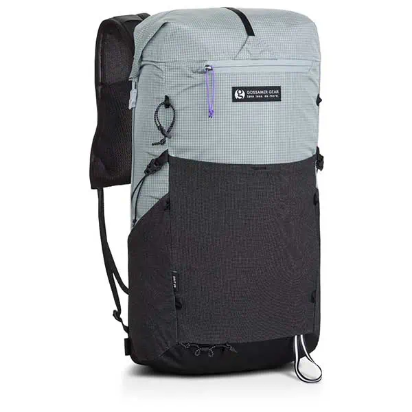 The Gossamer Gear Grit 28L Fastpack in gray and black boasts a logo patch front. It features multiple adjustable straps, a spacious front pocket, and a convenient loop at the bottom. The zippers are accented with stylish purple pulls for added flair.
