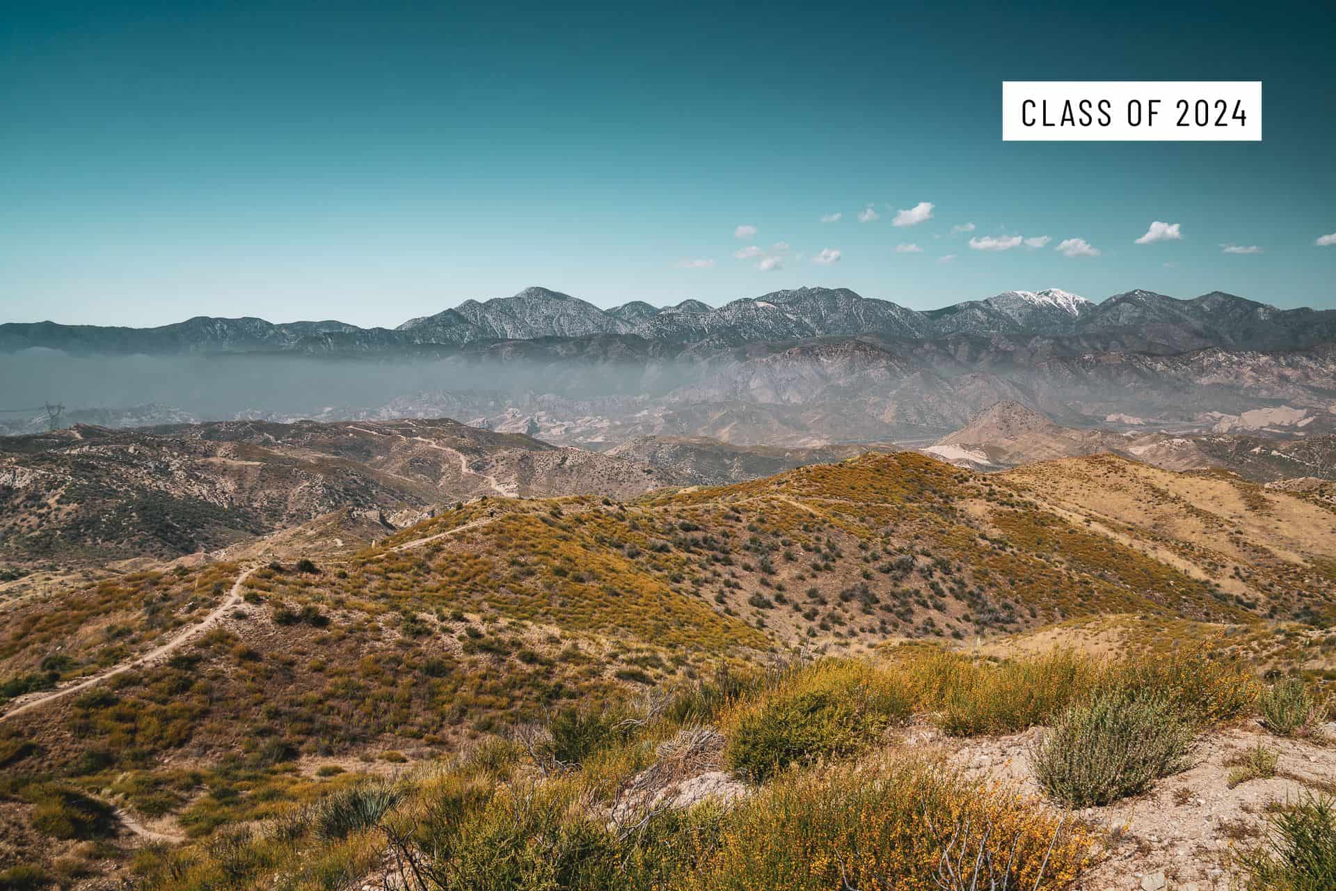 A scenic view of rolling hills covered in green and yellow vegetation with distant mountains under a clear blue sky. In the top right corner, text reads Class of 2024, celebrating the best pct moments of the year.