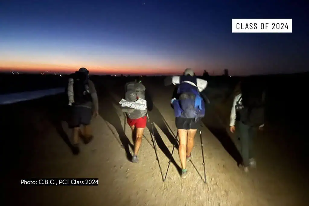 Four hikers with backpacks and trekking poles walk along a dirt path at dawn, silhouetted against a dark blue and orange sky. Text reads CLASS OF 2024 and “Photo: C.B.C., PCT Class 2024—discrimination on the Pacific Crest Trail 2024.”.