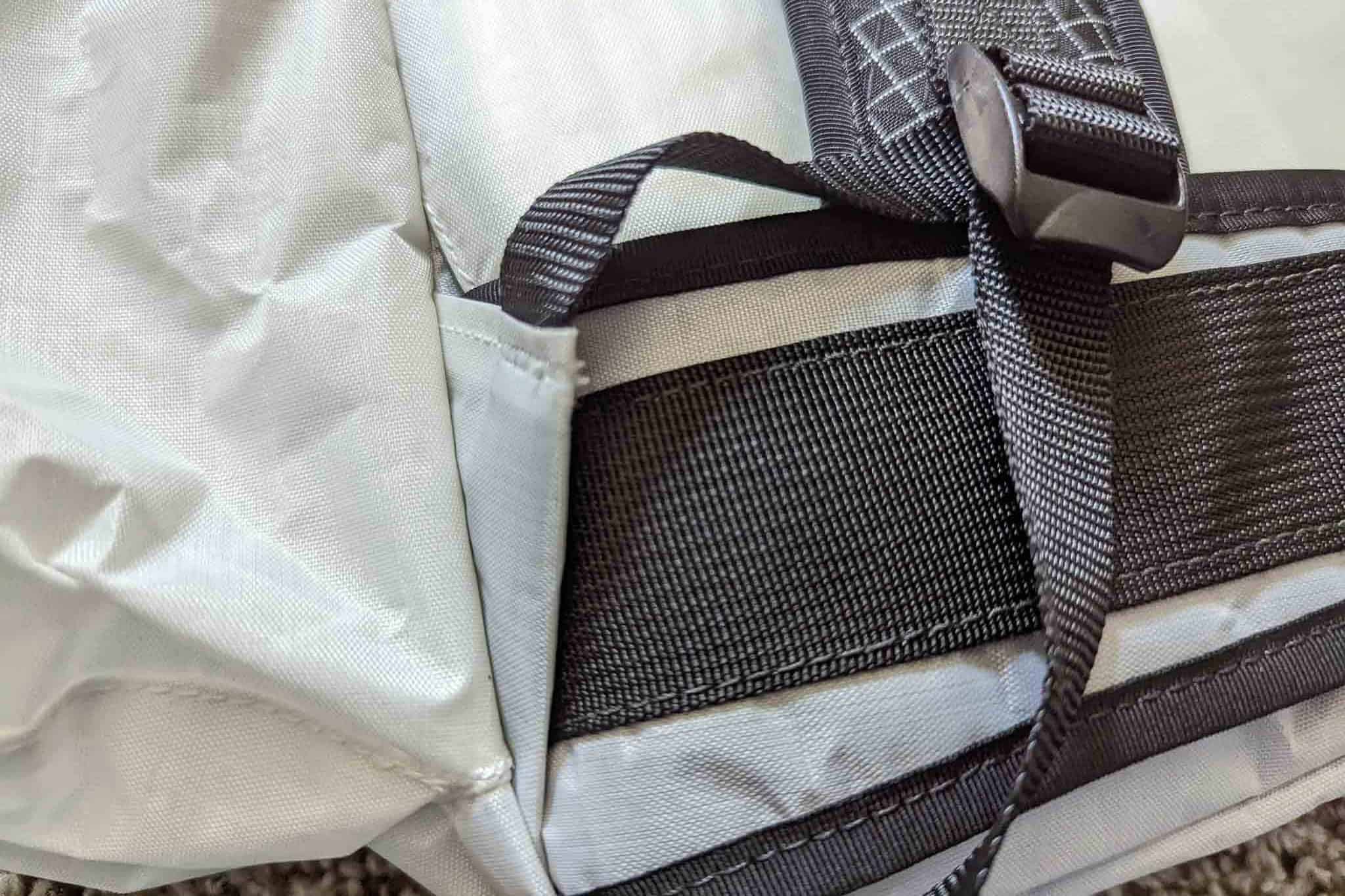 Close-up of a gray and black Rogue Panda Blue Ridge Handlebar Harness, showing a black strap, buckle, and stitching details on a fabric surface.