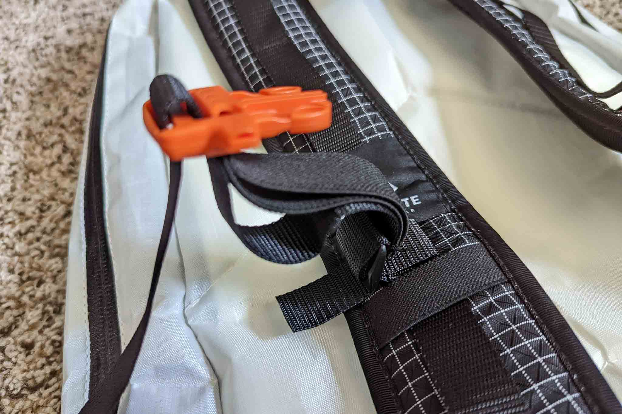 Close-up of a black and gray Rogue Panda Blue Ridge Handlebar Harness strap with orange plastic hardware, lying on a light-colored surface, showing detailed stitching and fabric texture.