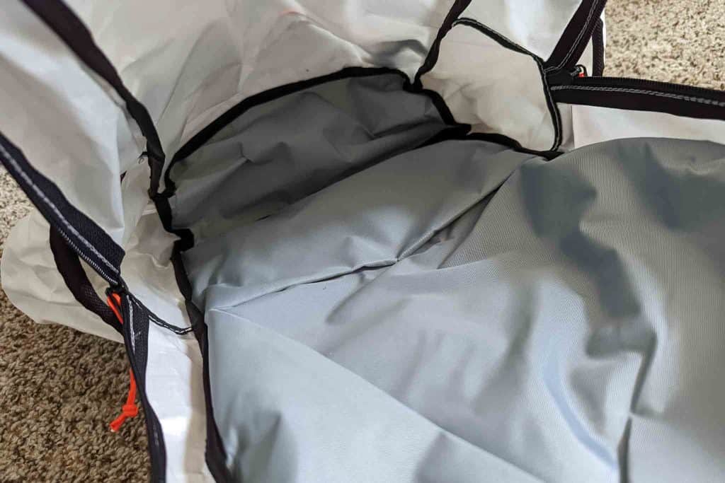 The image shows the inside of an empty gray and white backpack lying open on a carpeted floor, revealing its spacious interior and fabric lining—perfect for carrying gear like the Rogue Panda Blue Ridge Handlebar Harness.