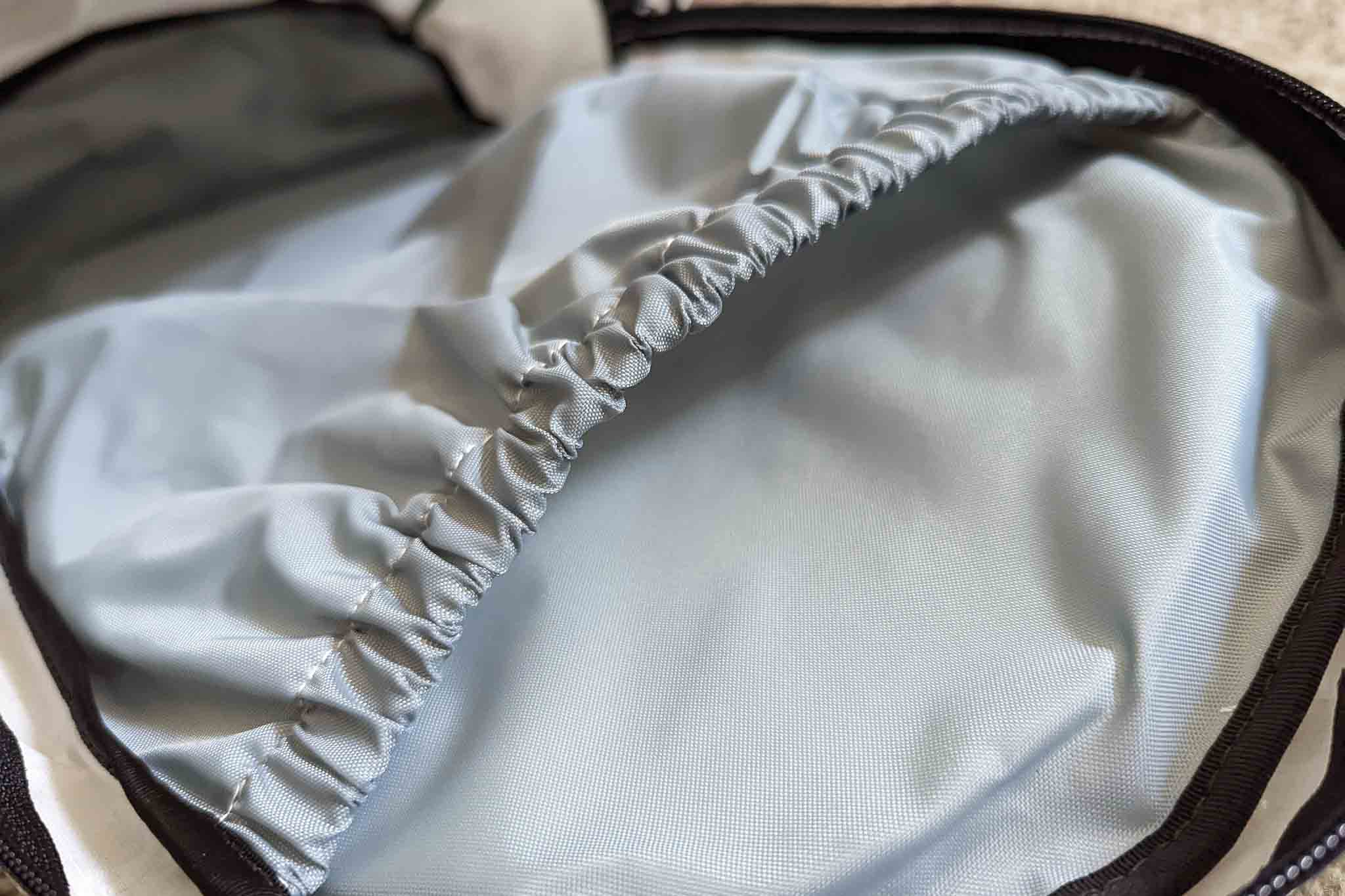 Close-up of the inside of a backpack showing a light gray fabric lining and an elastic-edged pocket, ideal for securing gear or accessories like the Rogue Panda Blue Ridge Handlebar Harness.